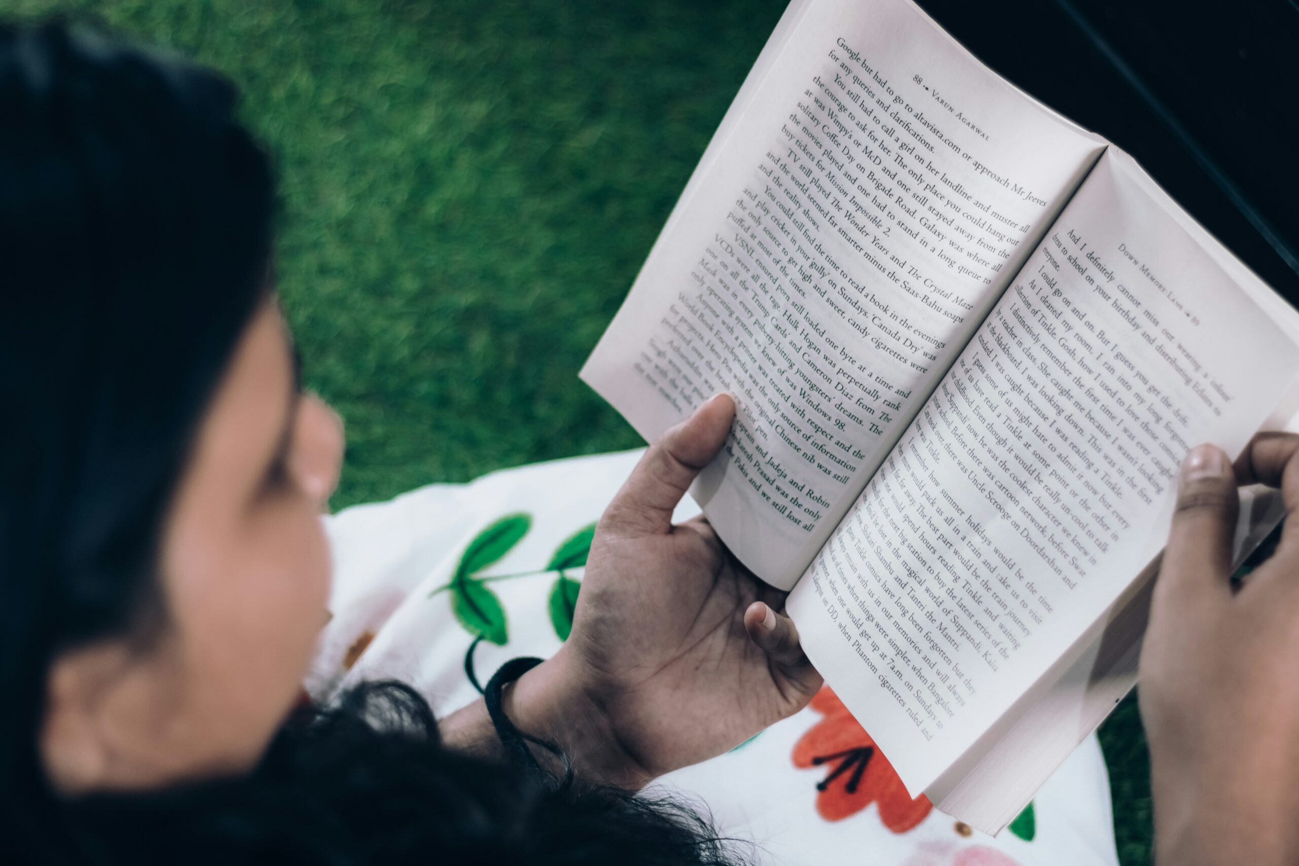 a woman is reading a book on the grass